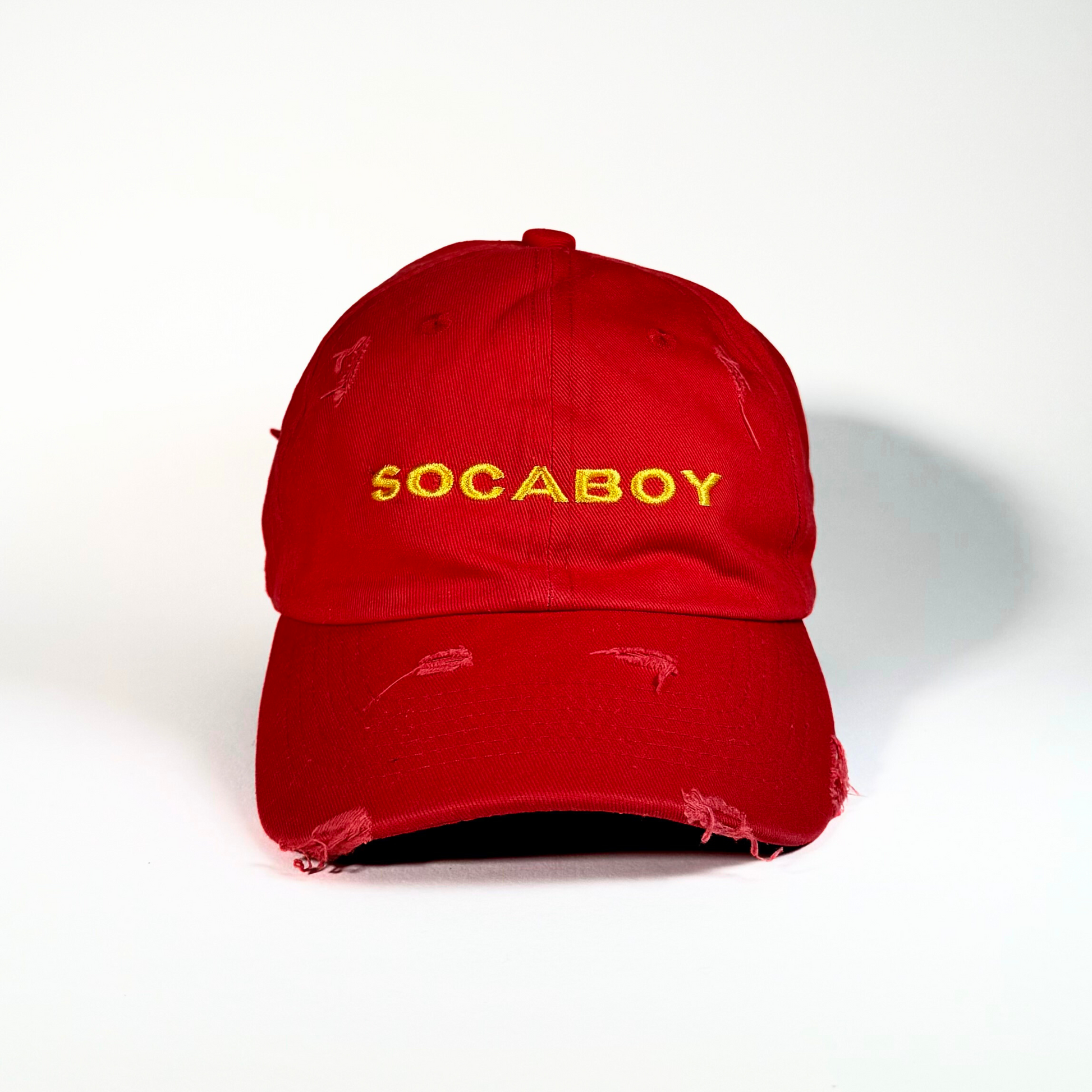 The front of the red Socaboy Rossa Cap is photographed against a white backdrop. The hat features the signature Socaboy logo in yellow and has a distressed effect on the brim and top of the cap.