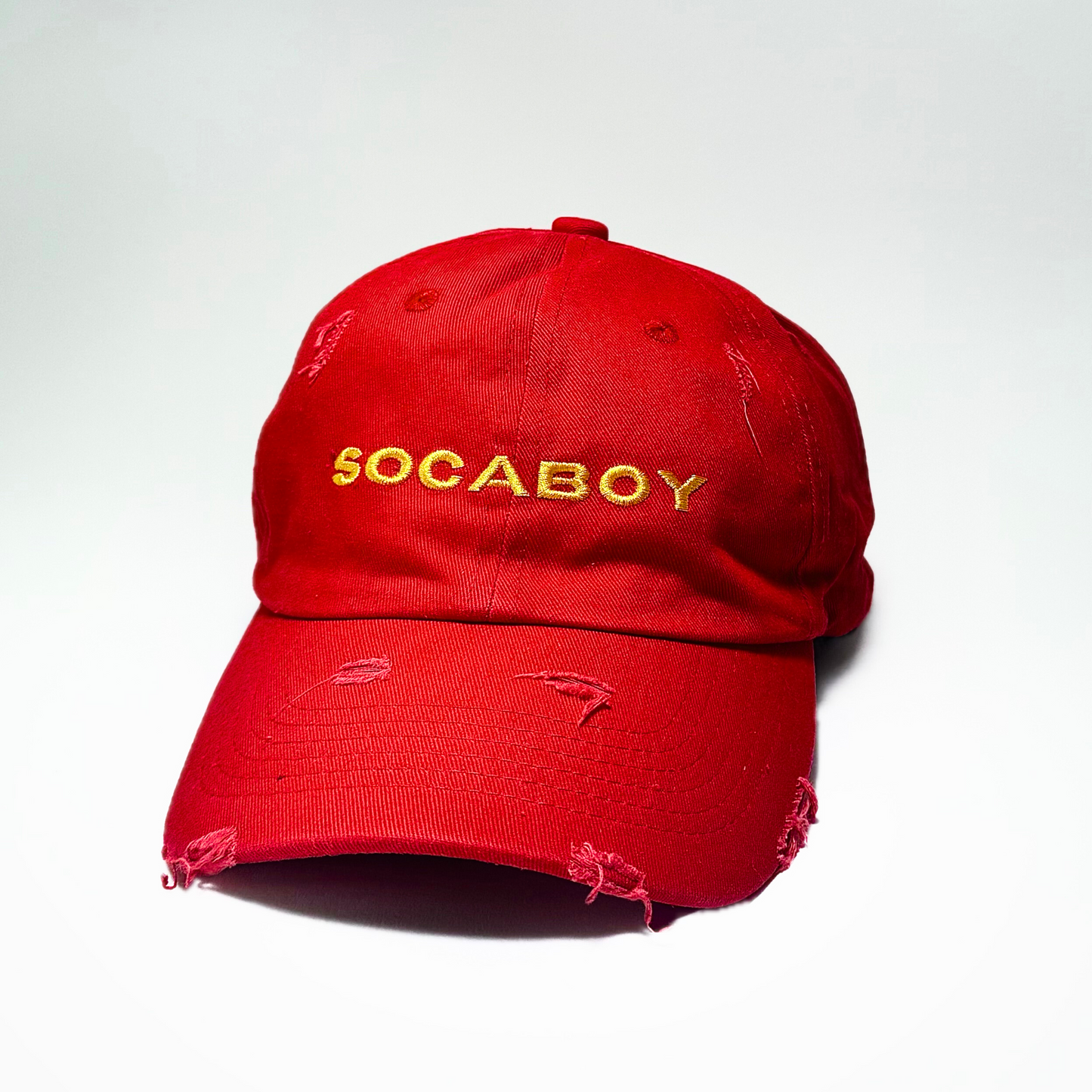 The front of the red Socaboy Rossa Cap is photographed against a white backdrop. The hat features the signature Socaboy logo in yellow and has a distressed effect on the brim and top of the cap.