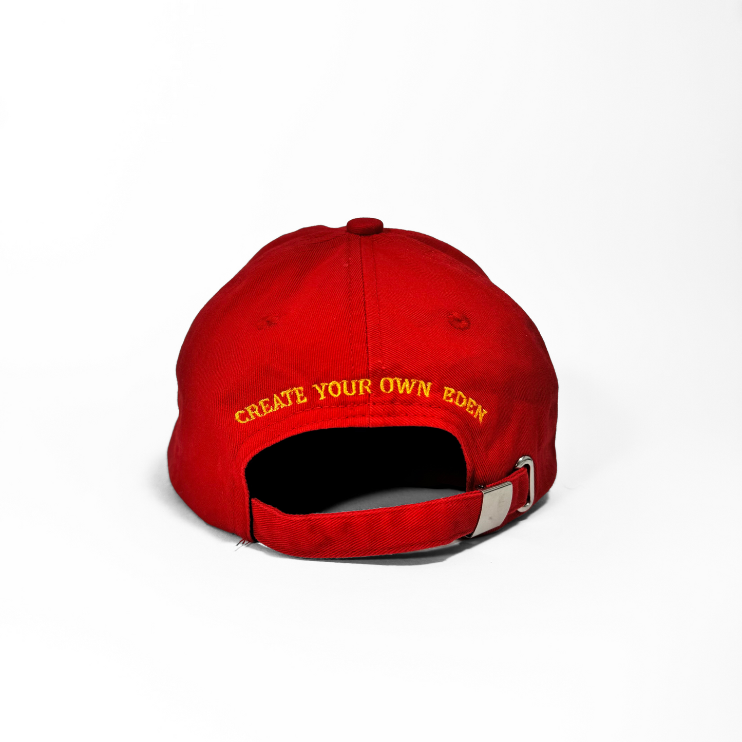 The back of the red Socaboy Rossa Cap photographed on a white backdrop. The back of the hat features the affirmation 'create your own eden' in yellow.